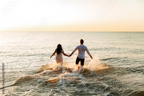 Loving couple in white clothes during a honeymoon at sea walk on the sand at a photoshoot Love Story, ocean coast, beach