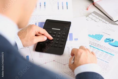 Black calculator and financial statistics on infographics at office table closeup. Internal Revenue Service inspector sum check, irs investigation, earnings, savings, loan and credit concept