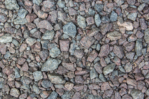 Gray gravel is used in the construction industry. Small road stone background. Granite gravel texture. Pattern of small gravel, rock or stone on the ground for background.