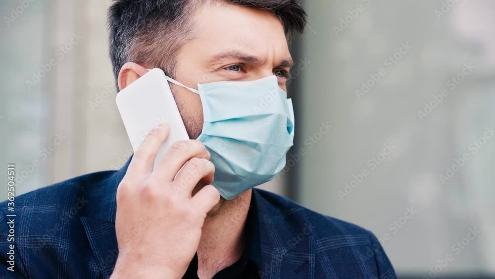 man in medical mask talking on smartphone outside man in medical mask talking on smartphone outside