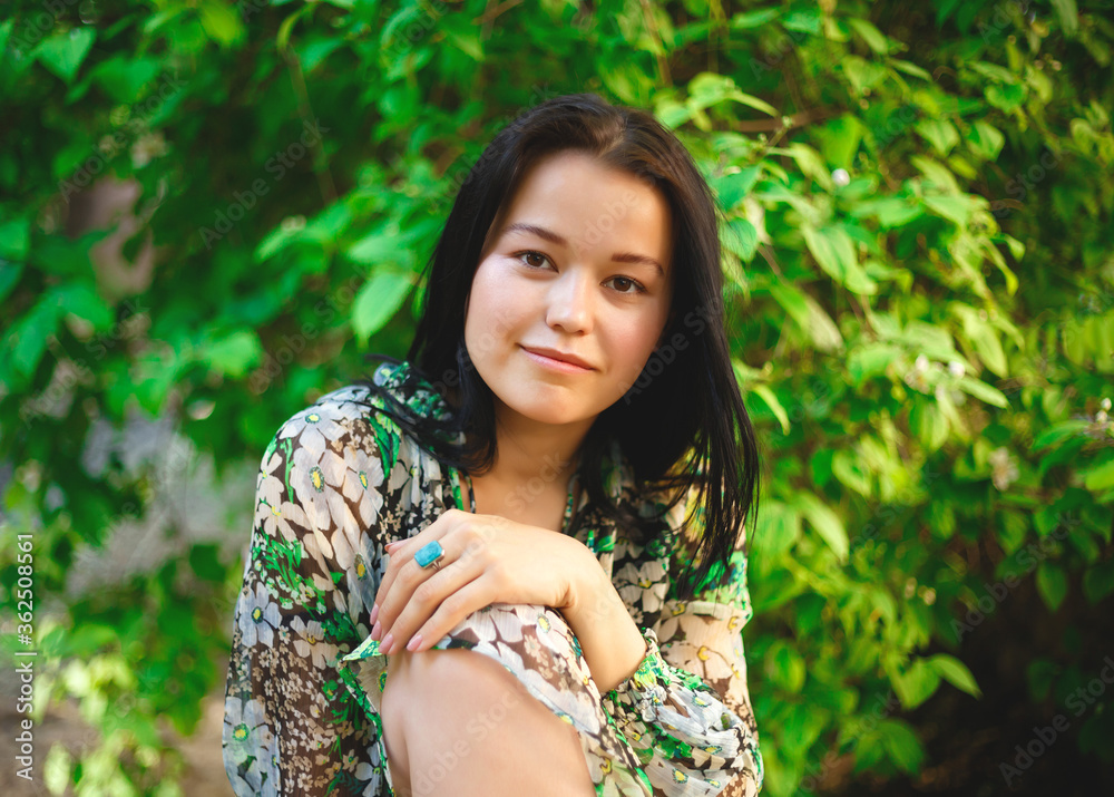 portrait of a beautiful smiling brunette on a background of greenery portrait of a beautiful smiling brunette on a background of greenery