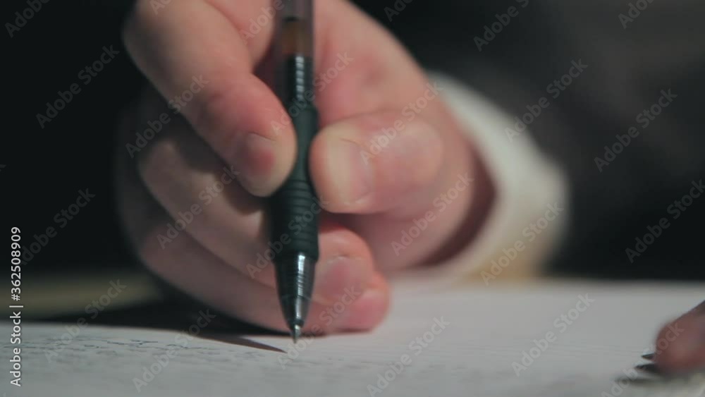 Person writing on paper with ink pen. Close up view of fingers gripping writing utensil and taking down information in spiral notebook. Late night idea recorded in memo or letter writing concept.