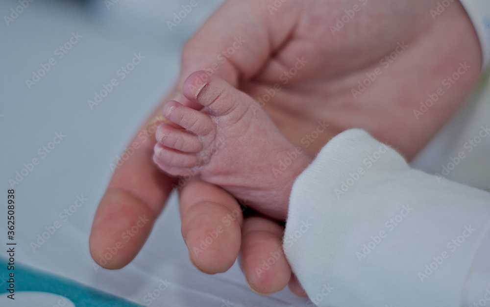 Foot of a newborn in the hospital holding his mother's hand Foot of a newborn in the hospital holding his mother's hand