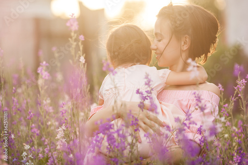 Pretty little girl and her mother with flowers. Family outdoors