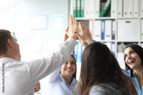 Smiling business people giving five after dealing and signing contract in their meeting room. Teamwork and partnership concept