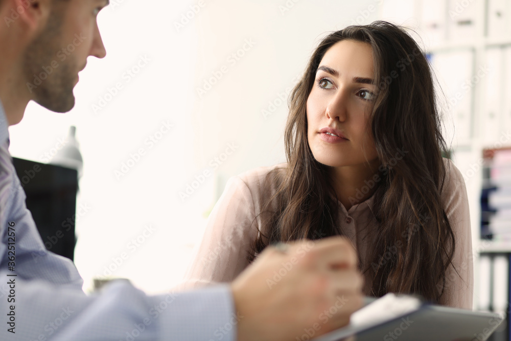 Two young employees looking at each other in the office while talking. Teamwork and partnership concept Two young employees looking at each other in the office while talking. Teamwork and partnership concept