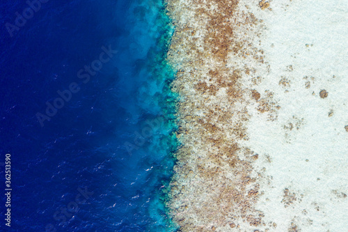 Cropped top above high angle aerial drone view of pure blue ocean water washing seashore stones coral reef wild luxurious destination tour hot sale early booking indonesia vietnam