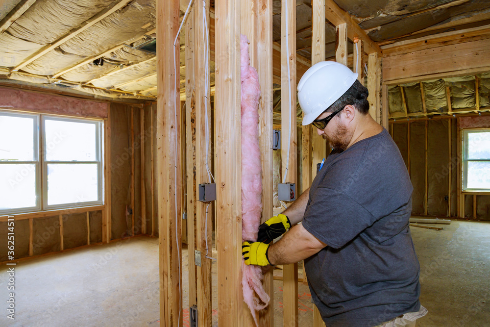 Closeup of worker hands in gloves insulating using mineral wool insulation staff in wooden frame for future walls for cold barrier.