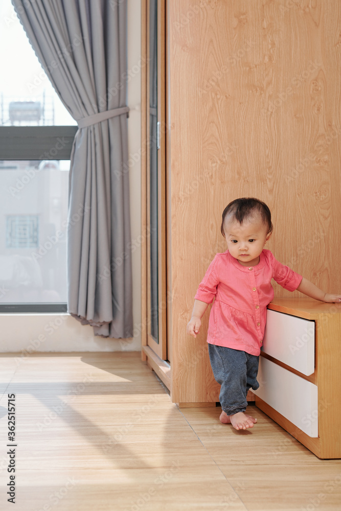 LIttle Vietnamese girl walking in living room when exploring apartment