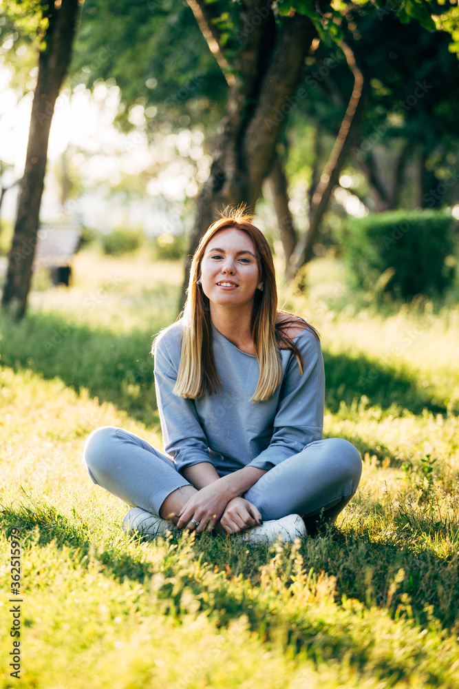 Girl in casual style sitting on the grass in the park