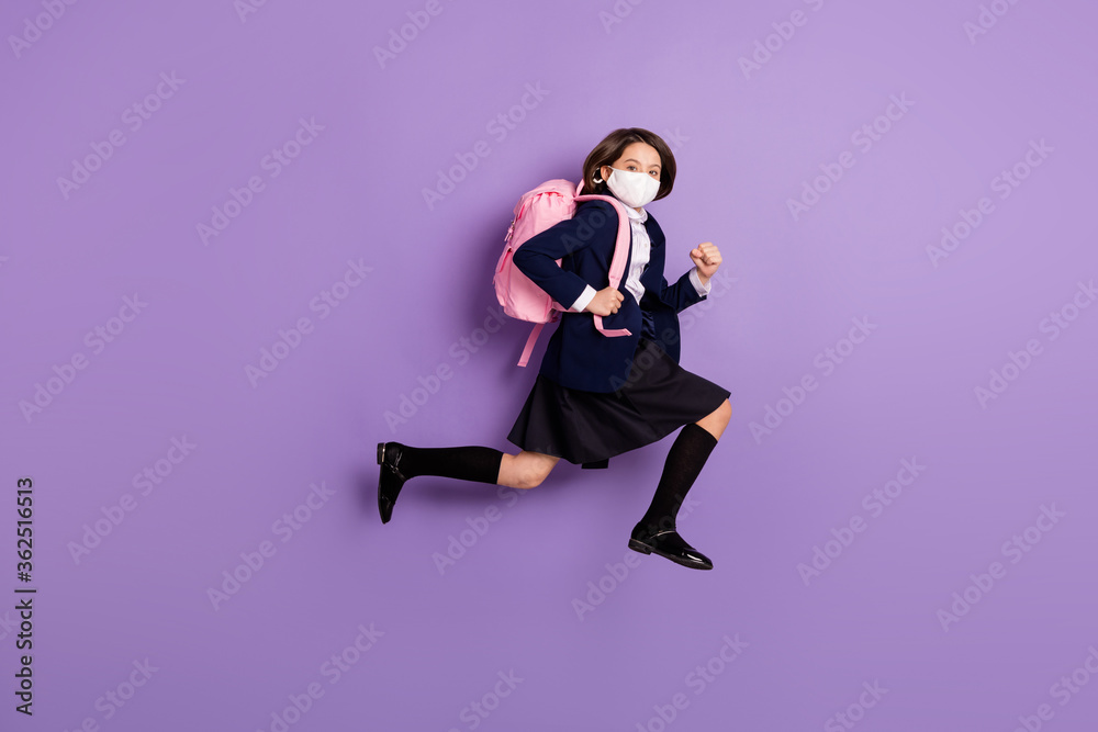 Full length body size profile side view of her she active small little energetic long-haired girl jumping running late to lesson grade wearing mask isolated lilac violet pastel color background Full length body size profile side view of her she active small little energetic long-haired girl jumping running late to lesson grade wearing mask isolated lilac violet pastel color background