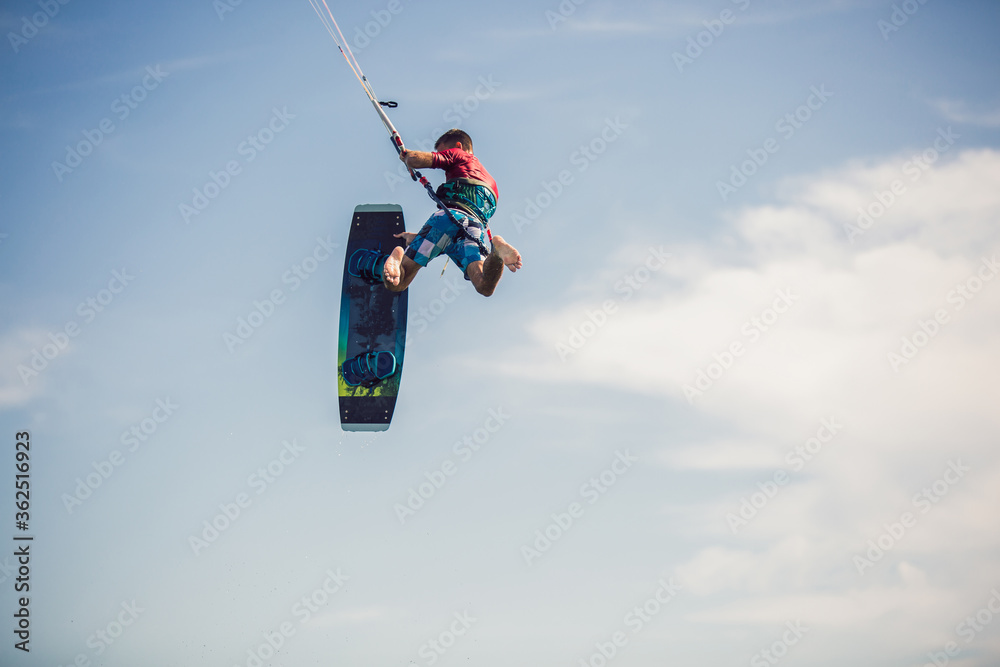 Professional kiter makes the difficult trick on a beautiful background. Kitesurfing Kiteboarding action photos man among waves quickly goes