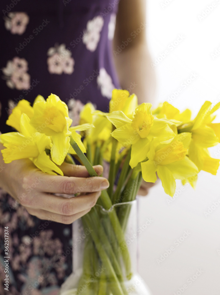 Woman arranging daffodils in vase