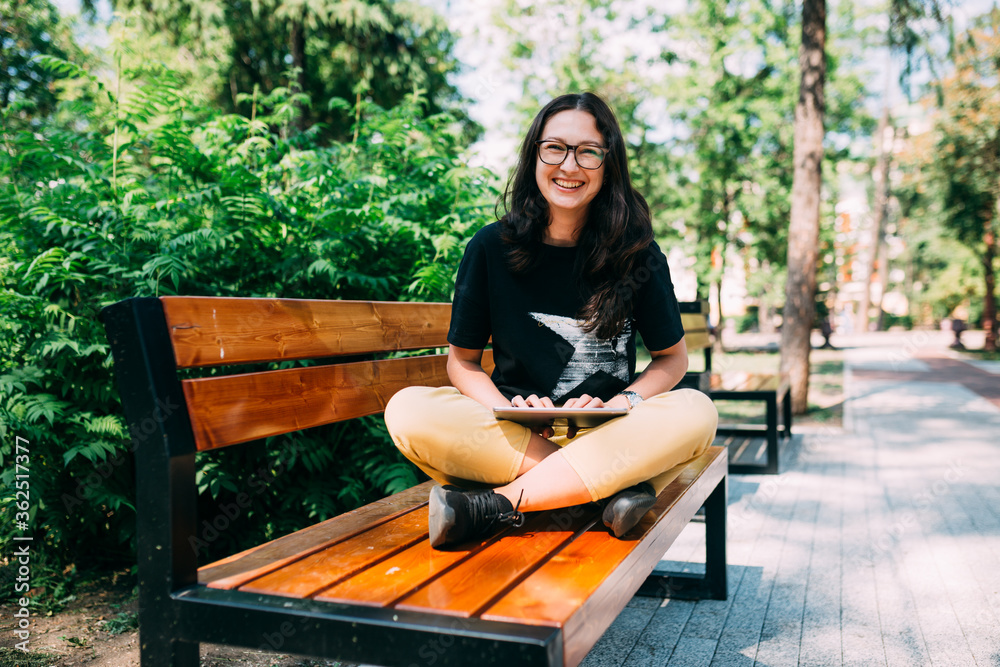 Beautiful young woman sitting on a bench with a tablet Beautiful young woman sitting on a bench with a tablet