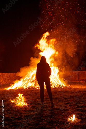 Silhouette of a woman in front of a giant bonfire