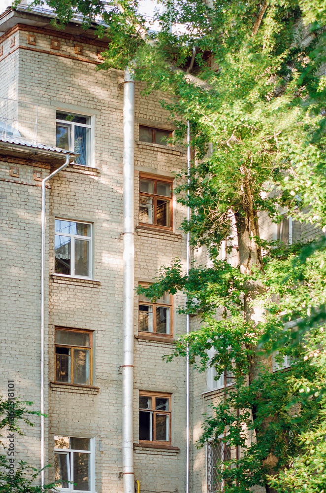 Close up cityscape day view of the beige brick building facades with windows. Typical residential building in Russia. Vertical photograph.