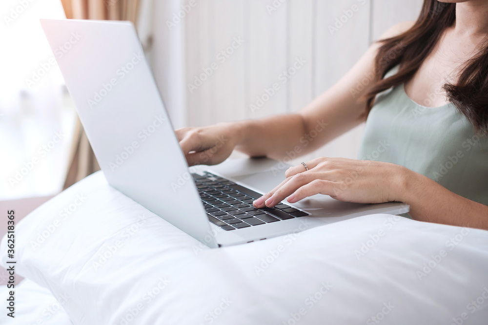 Happy casual woman sitting and using computer laptop on white pillow in bedroom. Young adult female Working from home or online shopping in morning. Freelancer, lifestyle and technology concepts Happy casual woman sitting and using computer laptop on white pillow in bedroom. Young adult female Working from home or online shopping in morning. Freelancer, lifestyle and technology concepts