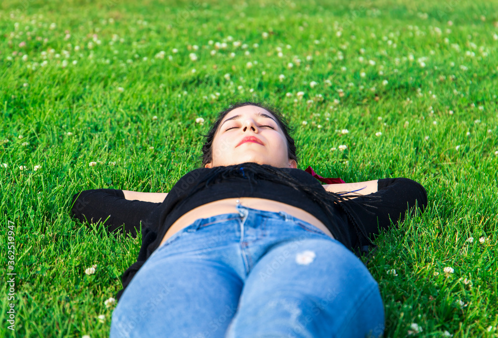 one woman lying on grass, very relaxed, enjoying nature, hands are behind her head, face is visible and recognizable one woman lying on grass, very relaxed, enjoying nature, hands are behind her head, face is visible and recognizable