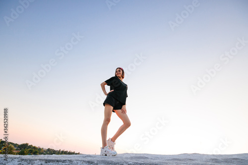 Sexy woman with a make up wearing black clothes outside at sunset. Featuring beautiful long legs