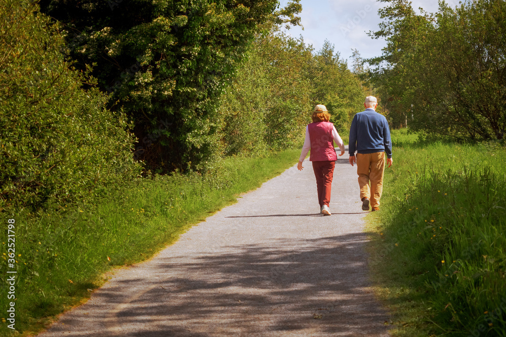 Fototapeta premium Old couple walking on a foot path on a warm sunny day. Concept active lifestyle.