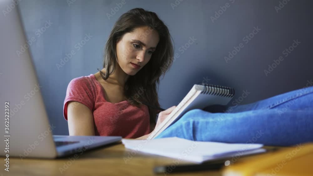 Busy young woman working, studying from home doing notes in notepad Busy young woman working, studying from home doing notes in notepad