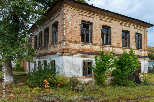 An old abandoned brick building overgrown with trees © Alexey Slyusarenko