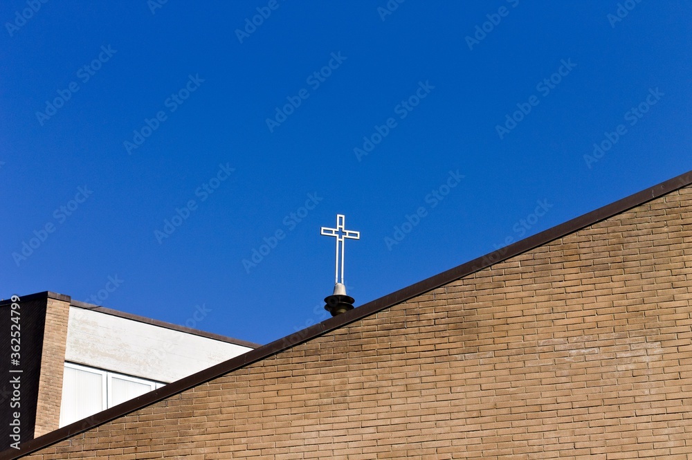Isolated crucifix on the roof of a modern church with a brick wall (Pesaro, Italy, Europe)