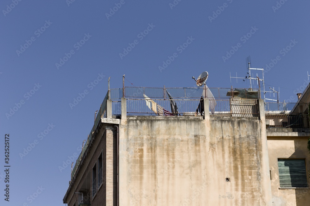 Some antennas and a satellite TV dish on the roof of a house near some clothes hanging on a wire (Pesaro, Italy, Europe) Some antennas and a satellite TV dish on the roof of a house near some clothes hanging on a wire (Pesaro, Italy, Europe)