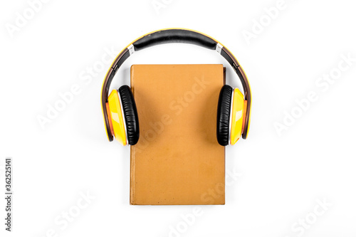 Book and yellow headphones on. White background top view