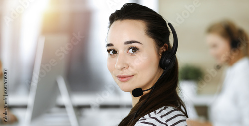 Business woman using headset for communication and consulting people at customer service office. Call center. Casual dress style