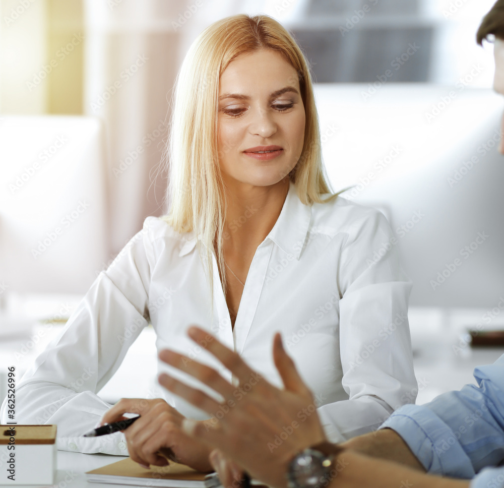 Group of business people discussing questions at meeting. Portrait of blond businesswoman in sunny office Group of business people discussing questions at meeting. Portrait of blond businesswoman in sunny office