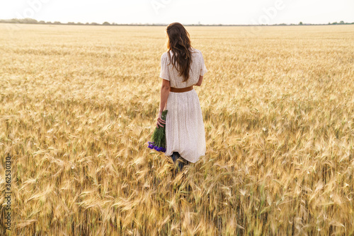 Photo of beautiful cute woman posing while walking on wheat field