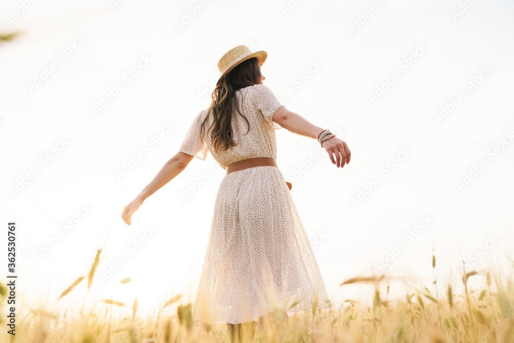 Photo from back of cute brunette woman dancing on wheat field