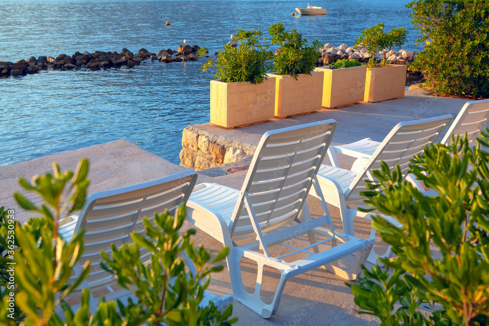 Fototapeta premium White sun loungers on a private beach . Perfect place on a seaside