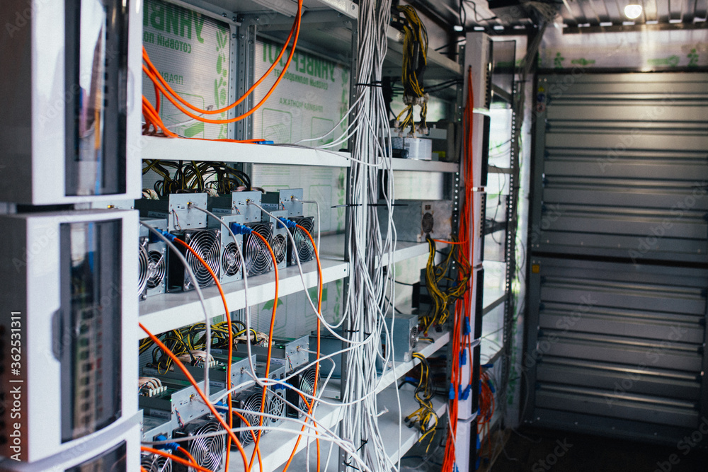 ASIC miners stand on a shelf and connected to electricity and the Internet