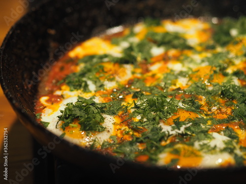 Image of fried eggs in a pan with tomatoes and herbs. Healthy summer natural food.