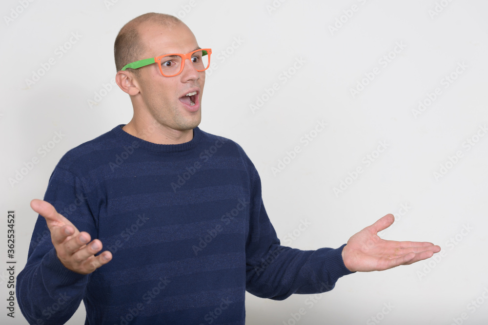 Portrait of happy young bald nerd man looking surprised Portrait of happy young bald nerd man looking surprised