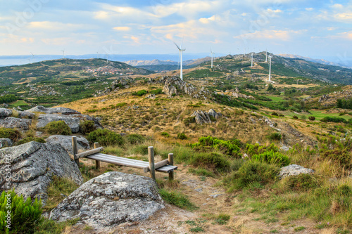 Beautiful landscape of Serra do Caramulo in Portugal, at sunset, with wooden bench in the foreground as a viewpoint for the long view, including the wind farm.