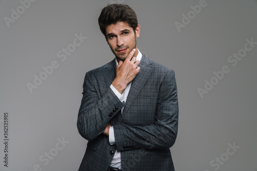 Photo of pleased businessman in jacket posing and smiling at camera