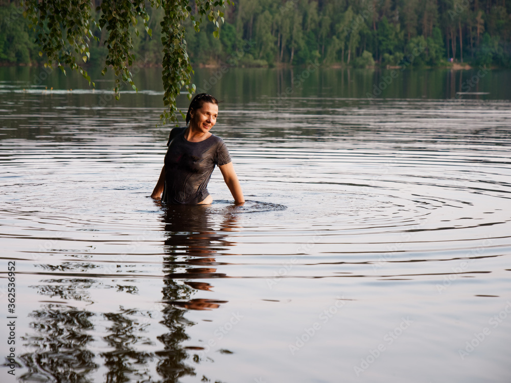 Fototapeta premium beautiful girl bathes in a lake at sunset
