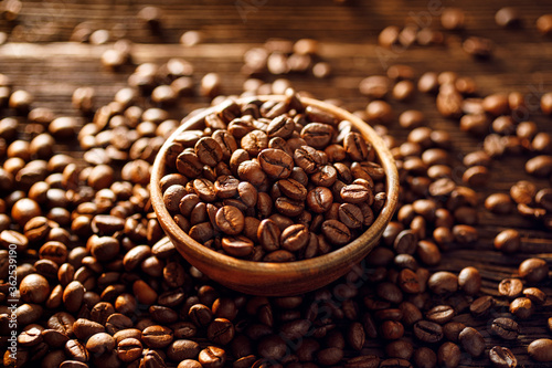 Coffee beans in a wooden bowl among the scattered coffee