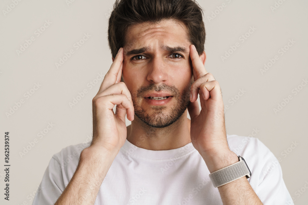 Portrait of unhappy young man with headache rubbing his temples Portrait of unhappy young man with headache rubbing his temples