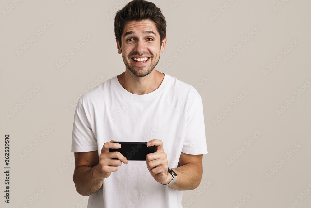 Portrait of unshaven excited man playing online game on mobile phone Portrait of unshaven excited man playing online game on mobile phone
