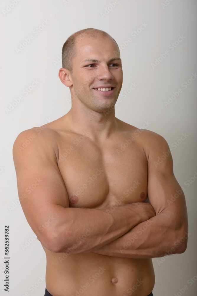 Happy young muscular bald man thinking with arms crossed shirtless