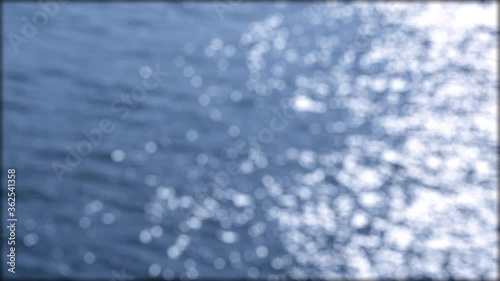 Sunlight shines on the surface of the river water. Sunrays with blurred bokeh effect.