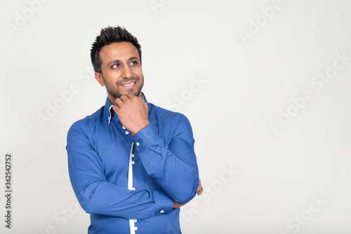 Portrait of happy bearded Indian businessman thinking