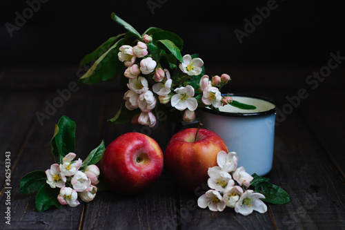 Still life with apples and flowers of apple tree on wooden table.