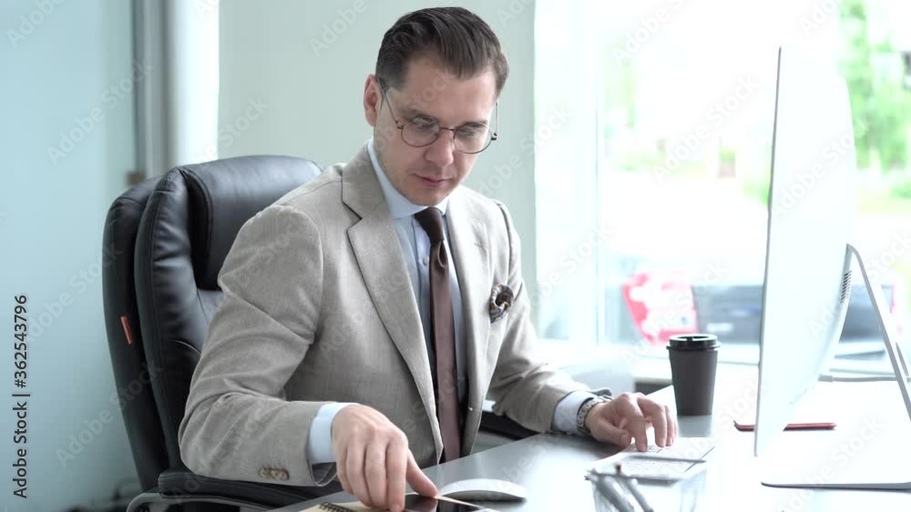 Smiling young businessman typing on computer keyboard and looking at computer monitor Smiling young businessman typing on computer keyboard and looking at computer monitor