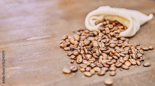Coffee beans coming out of a sack on a wooden table