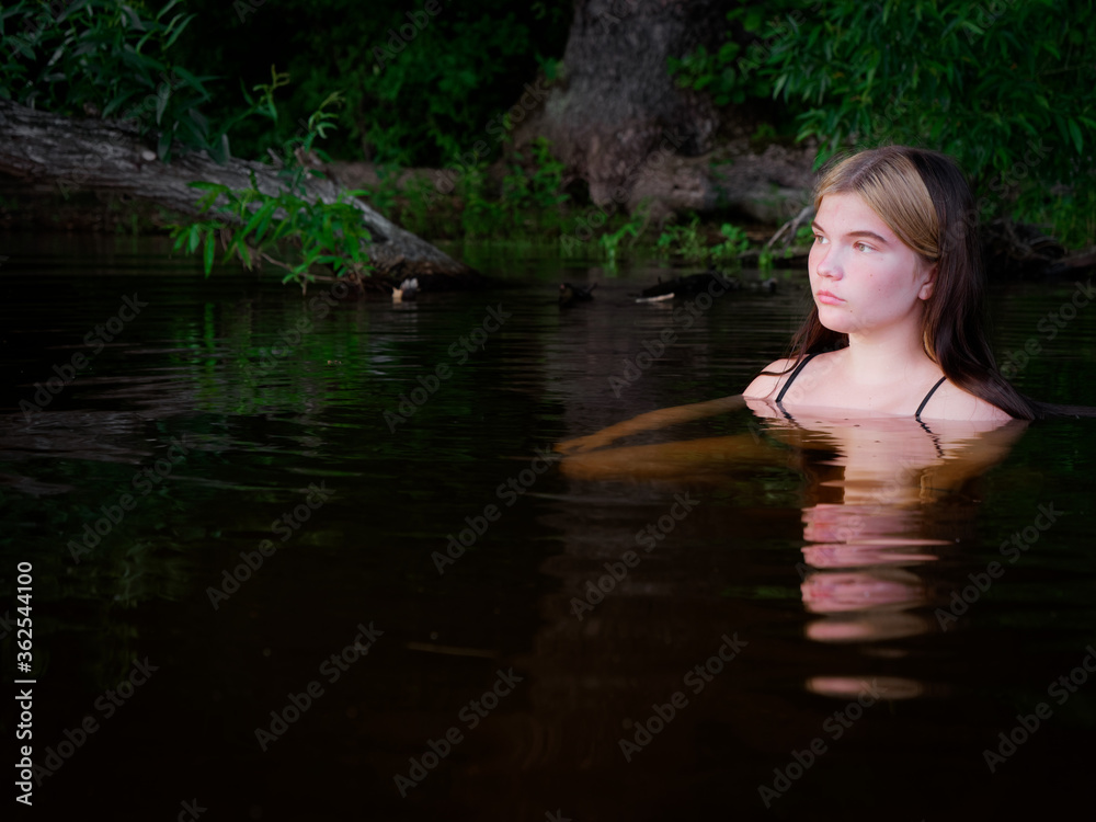 girl is reflected in the dark water at sunset girl is reflected in the dark water at sunset